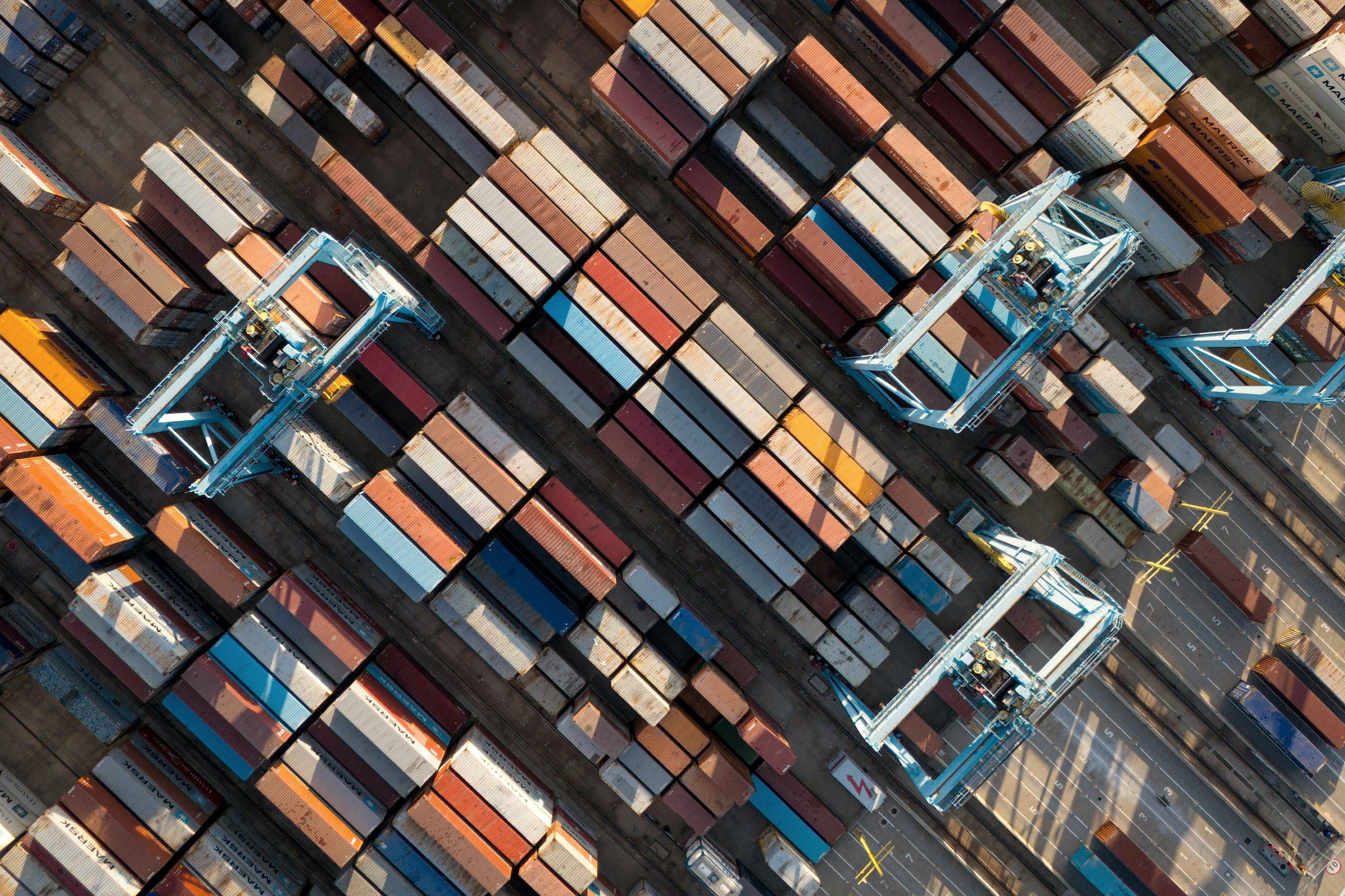 An aerial view of a container yard, straddle carriers moving between the stacks